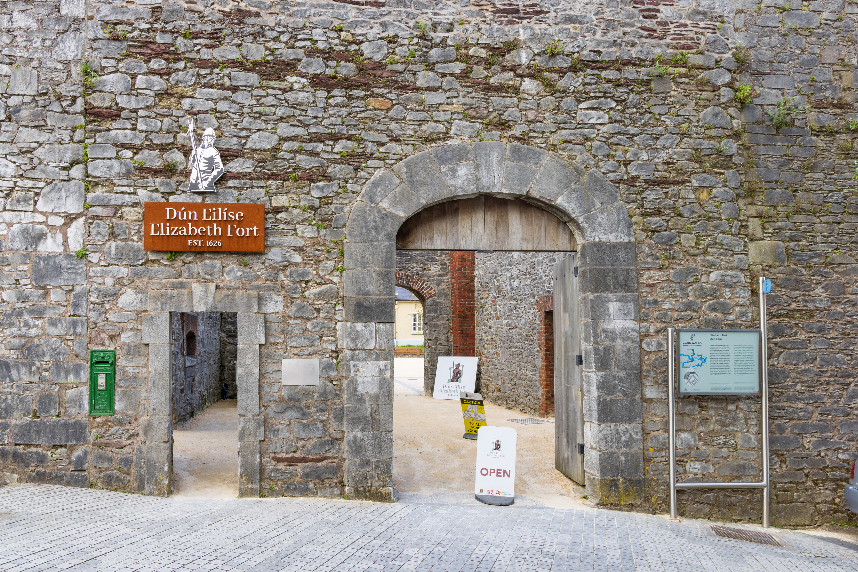 The stone entrance to Elizabeth Fort in Cork, with an arched gateway, bilingual sign and historic defensive walls.